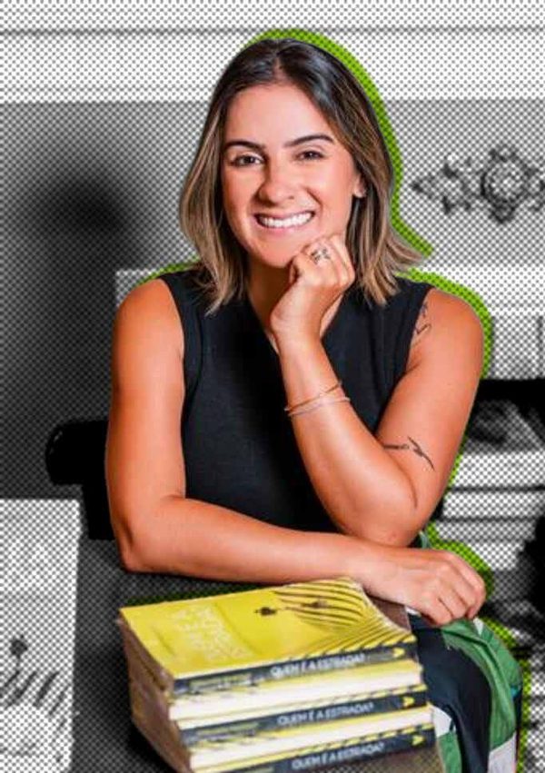 Fernanda Pandolfi sorrindo, apoiada em uma pilha de livros